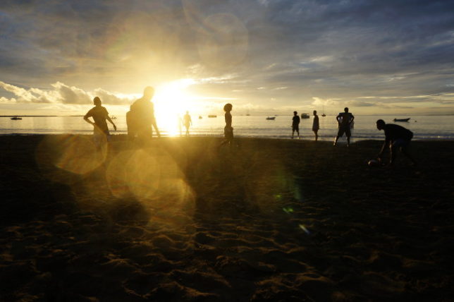 Guys are playing Rugby on the beach.